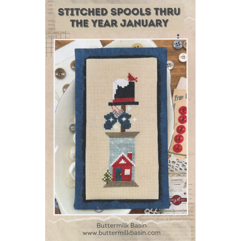 Cross-stitch pattern cover showing a winter hat, bow, and red house under the title January.