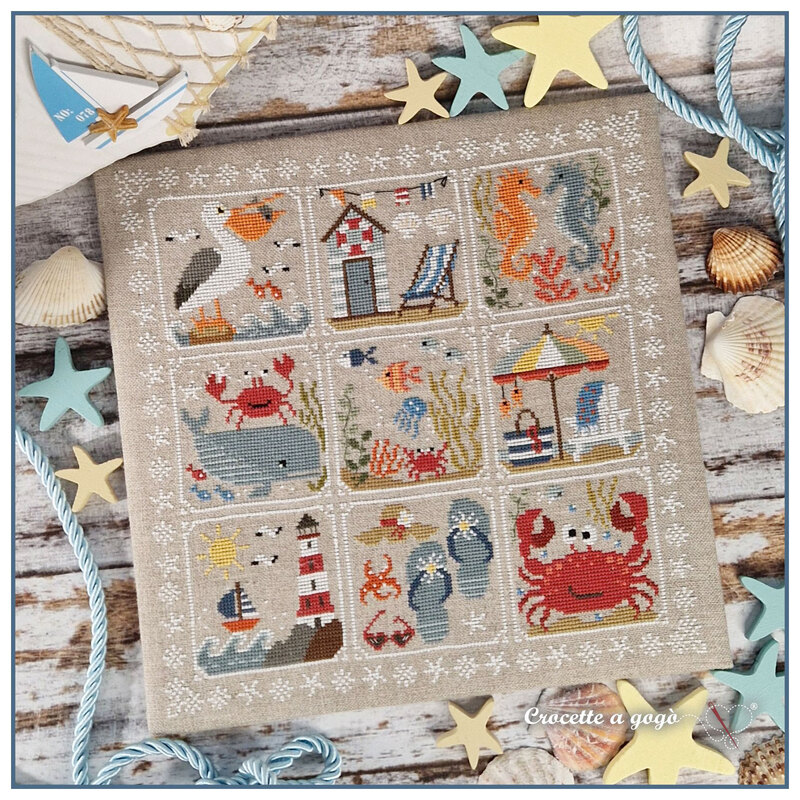 Image of the completed cross stitch project featuring 9 squares with nautical themed motifs surrounded by a white seashell border
