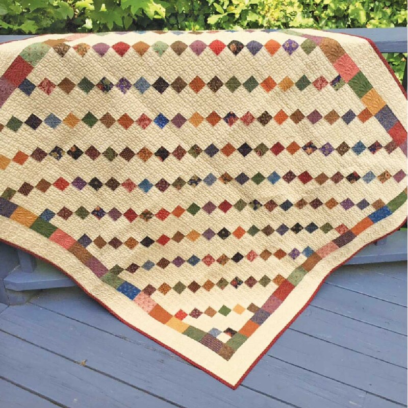 Image of finished Simplicity quilt in warm accenting colors against cream.