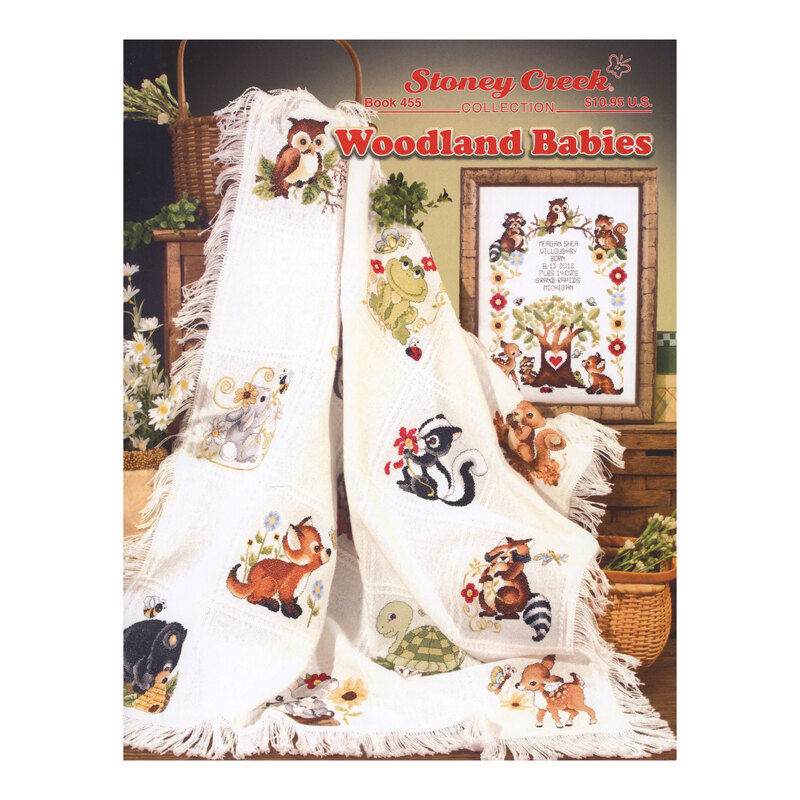 Front cover of the Woodland Babies pattern booklet showing the finished afghan hanging on a basket and the finished sampler sitting on a wooden crate.