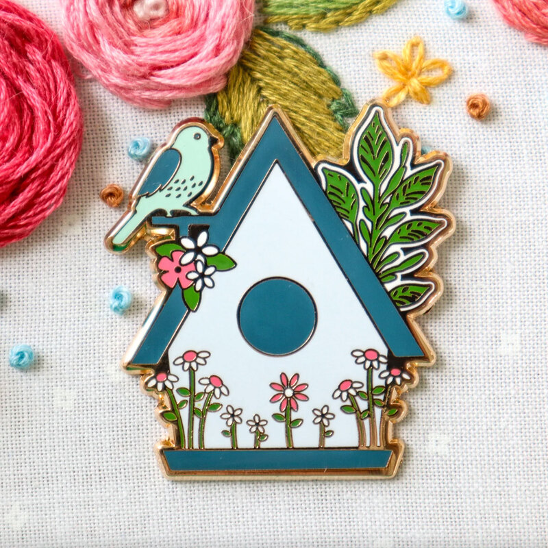 The birdhouse needle miner displayed on a hand embroidery project.