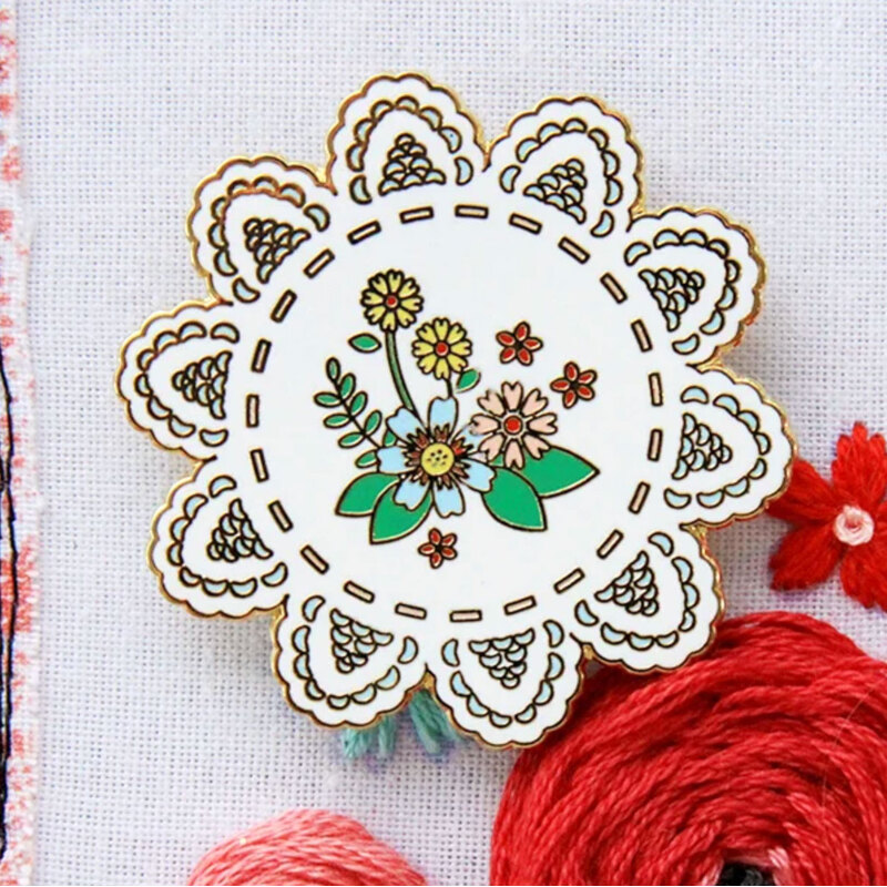 The vintage floral doily needle miner displayed on a hand embroidery project.