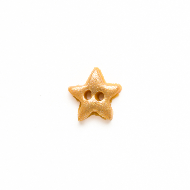 Small metallic gold clay star button, isolated on a white background. 