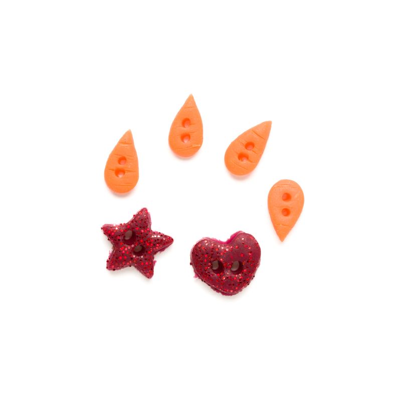 Clay button set of red glitter charms and four orange carrot noses, isolated on a white background. 