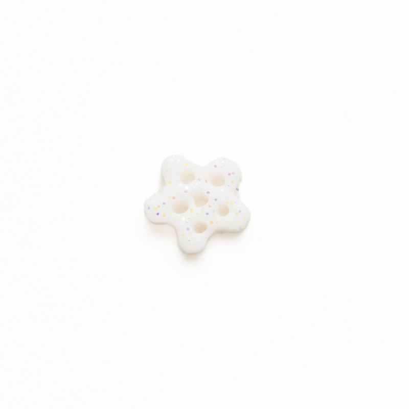 Small white glittery clay snowflake button, isolated on a white background. 