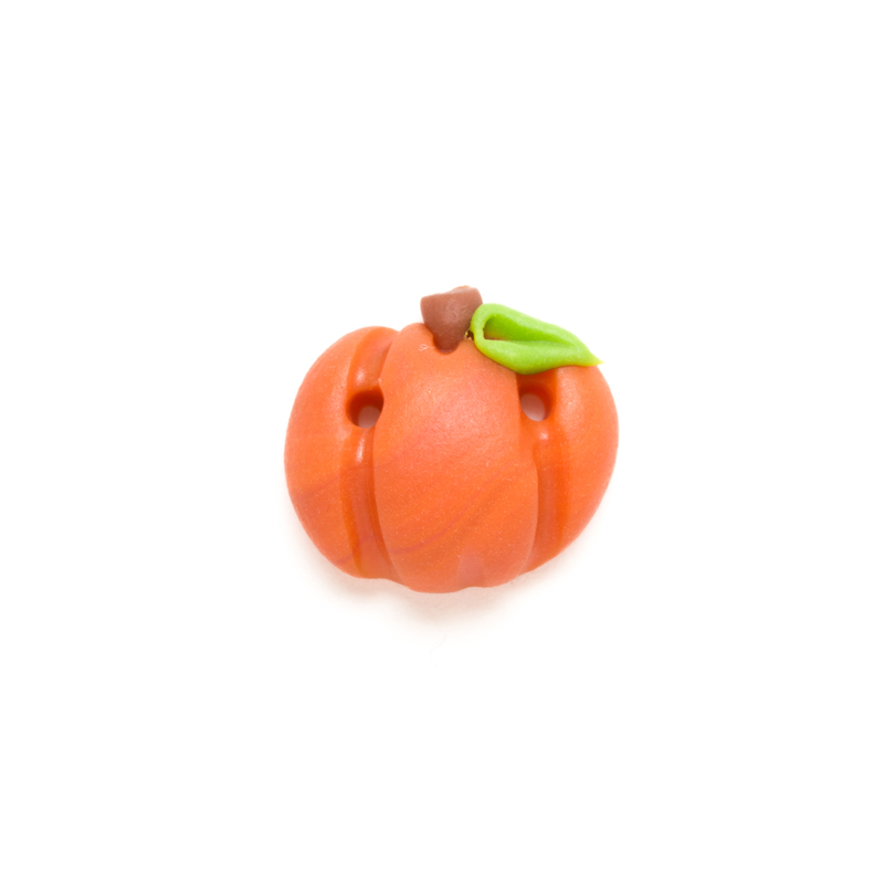 Small orange pumpkin clay button with a green leaf on a white background.