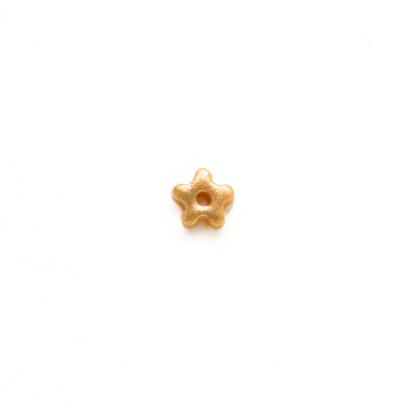 Tiny metallic gold clay star button, isolated on a white background. 