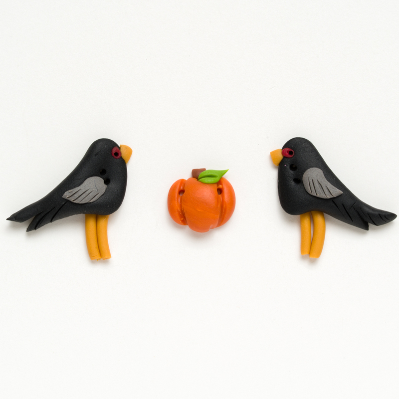 Clay button set of two black crows and a pumpkin, isolated on a white background. 