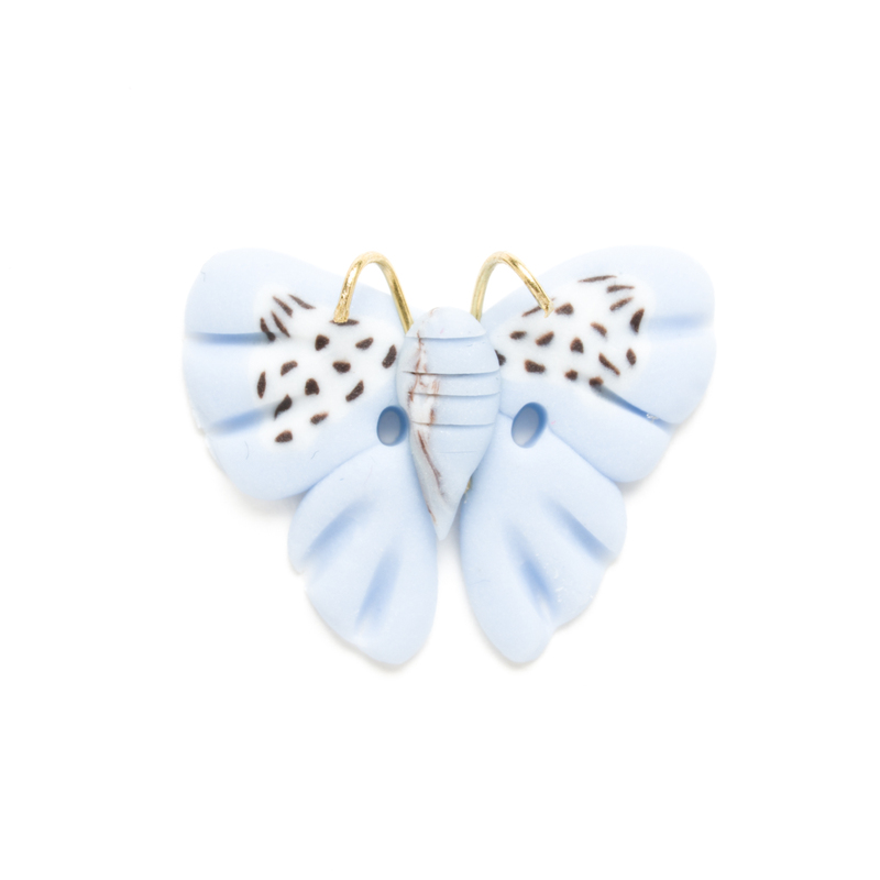 Light blue butterfly clay button with brown speckles, isolated on a white background. 