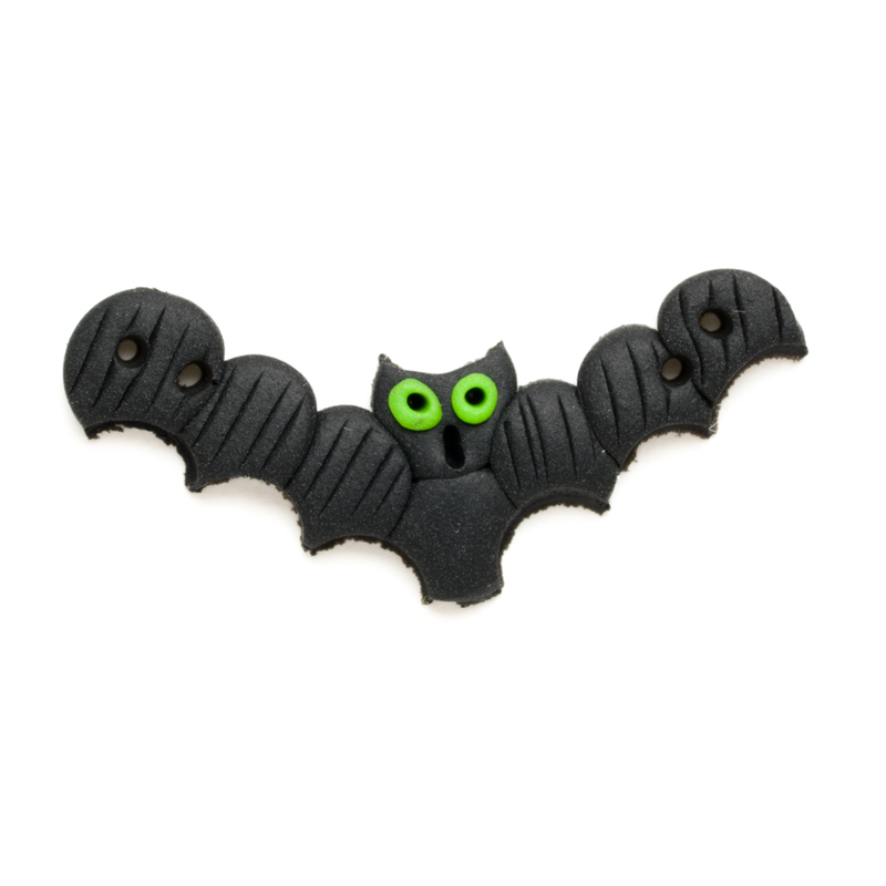 A black clay button of a bat with curvy wings and green eyes.