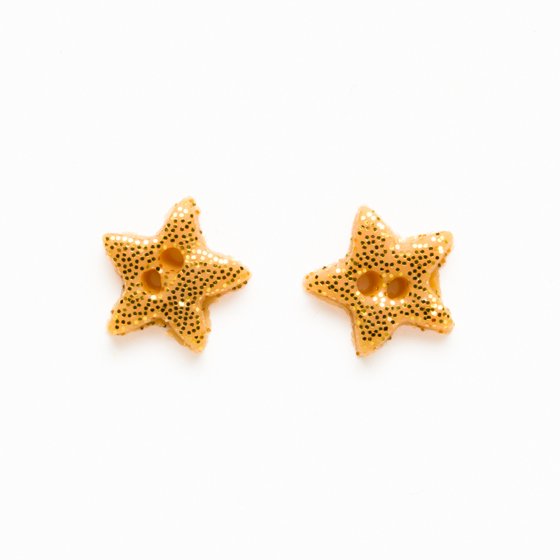 Two small star-shaped gold beads on a white background.