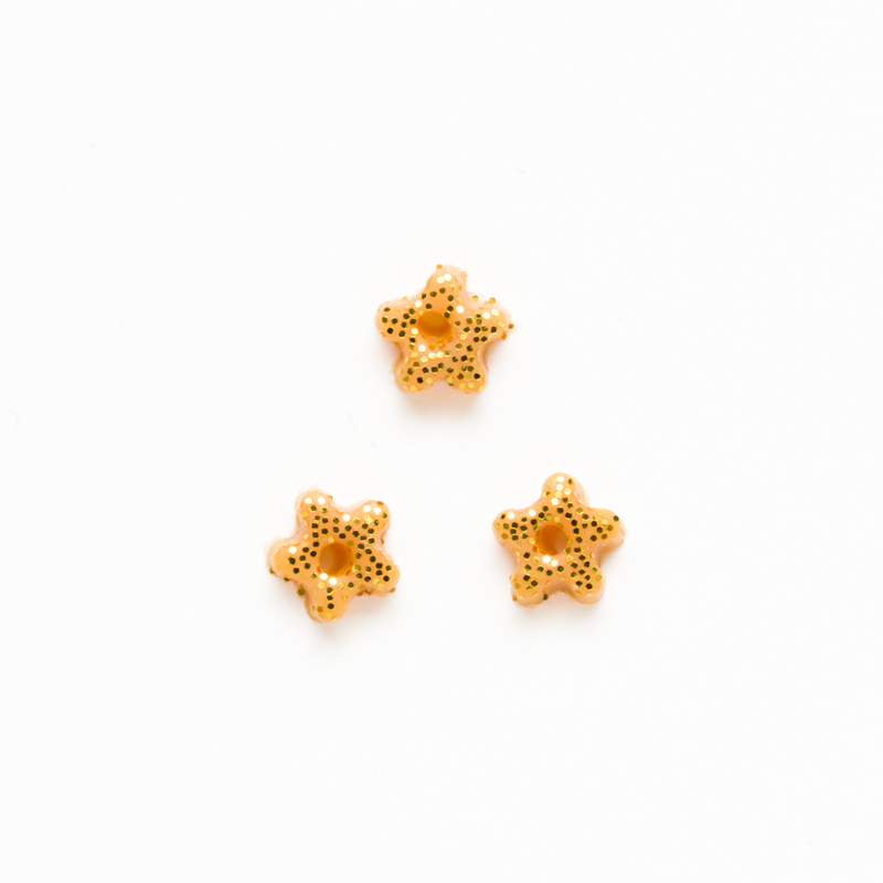 Three small star-shaped gold beads on a white background.