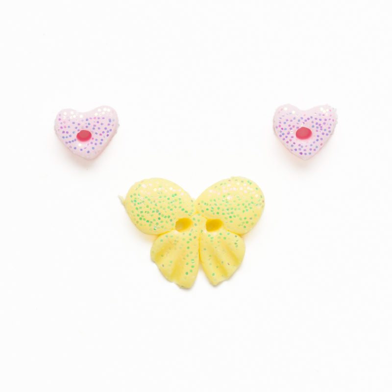 Clay button set of two pink glitter hearts and a glittering yellow butterfly, isolated on a white background. 