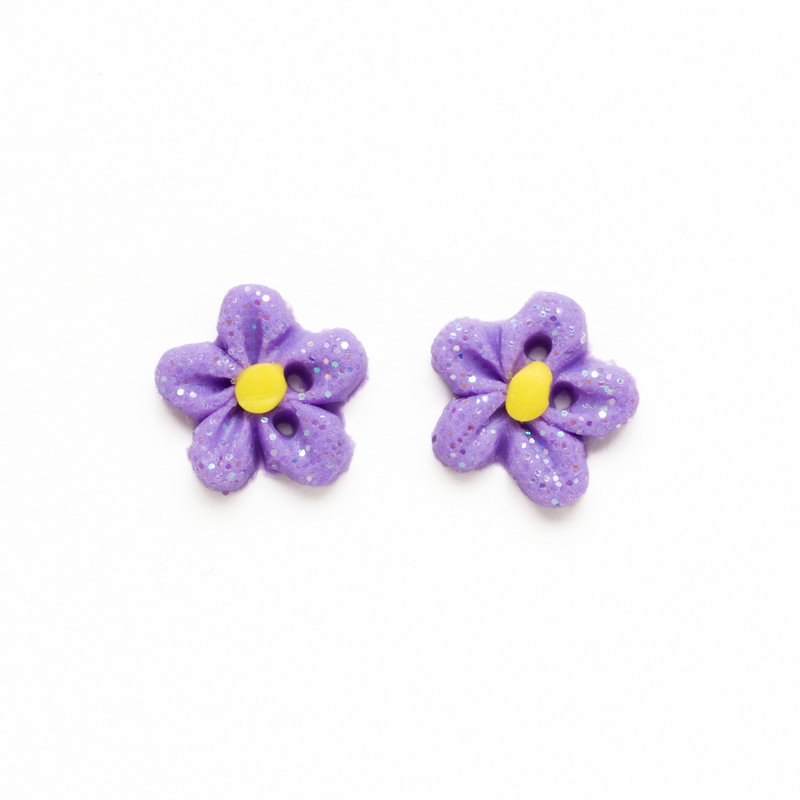 Two small light purple glitter flower clay buttons with yellow clay centers, isolated on a white background.