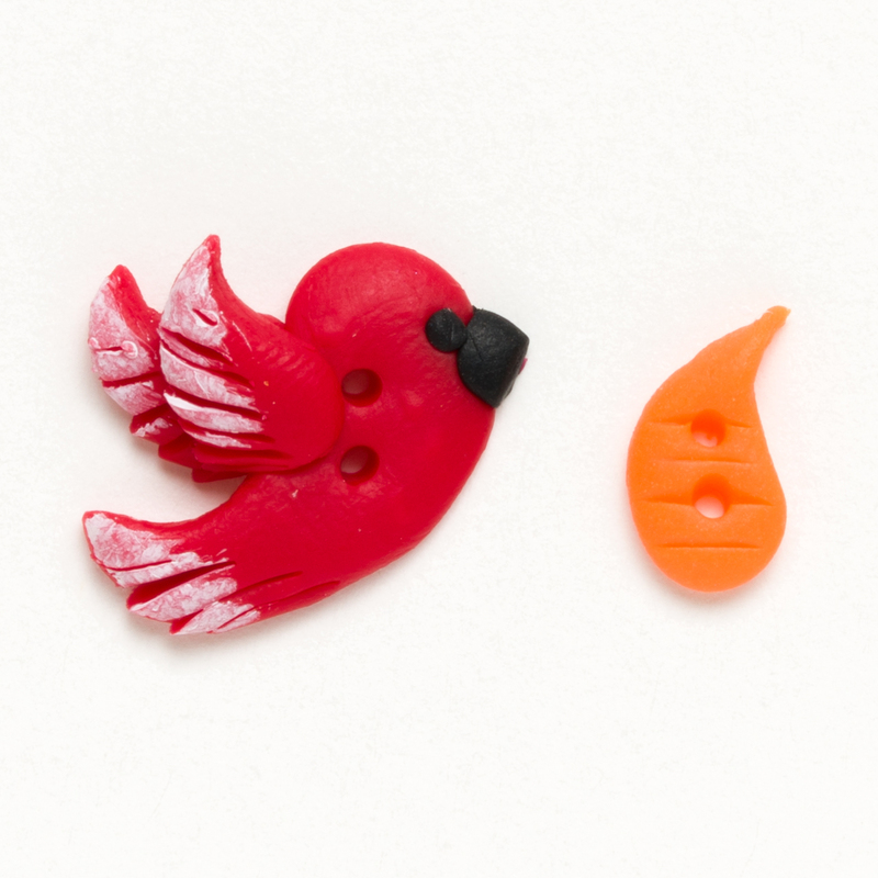 Red cardinal and orange carrot clay button, isolated on a white background. 