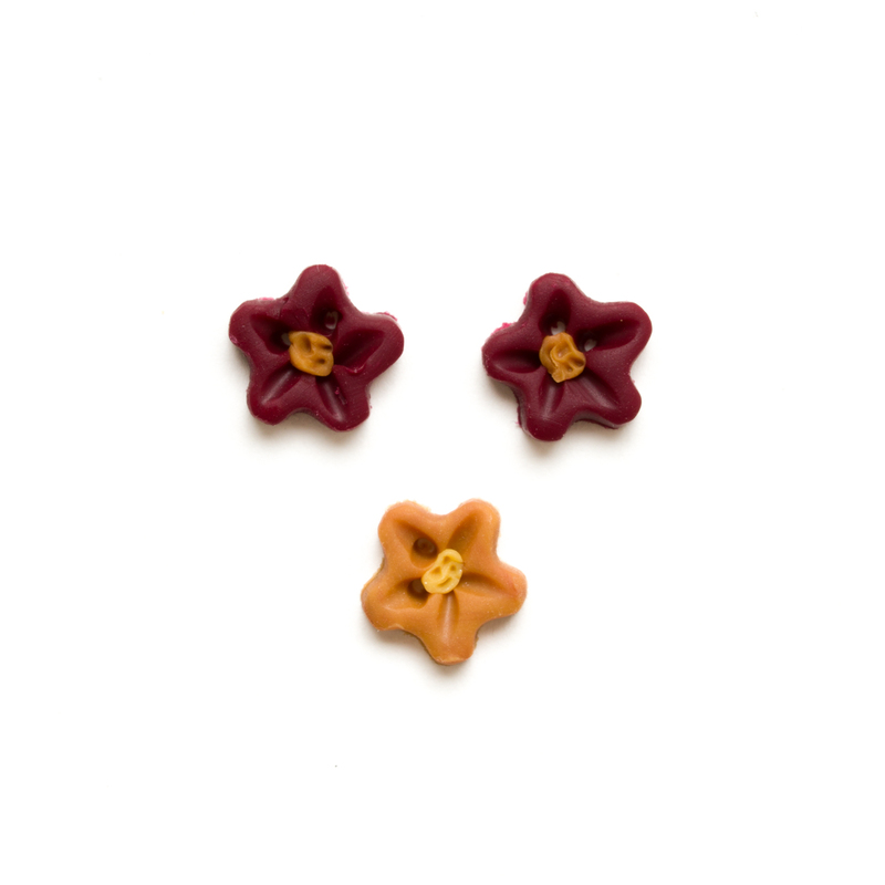 Three small red and yellow clay flower buttons isolated on a white background. 