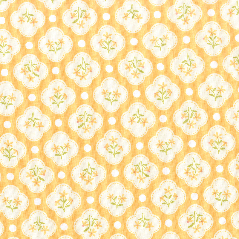 This golden yellow fabric features white quatrefoils amongst white dots. 