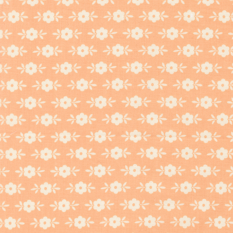 This pastel peach fabric features white floral motifs. 
