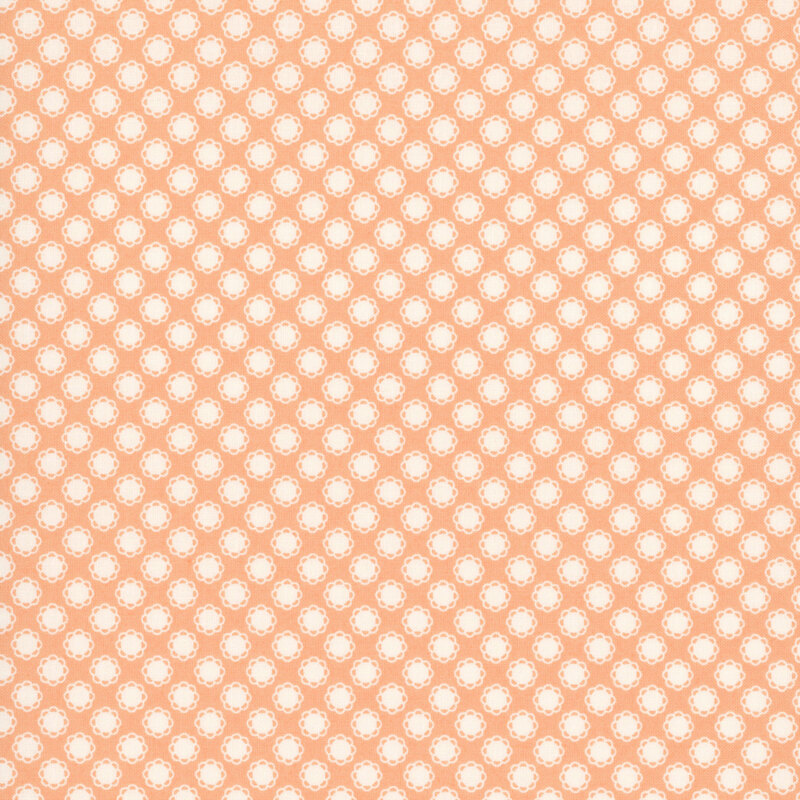 This soft peach fabric features white doily motifs. 