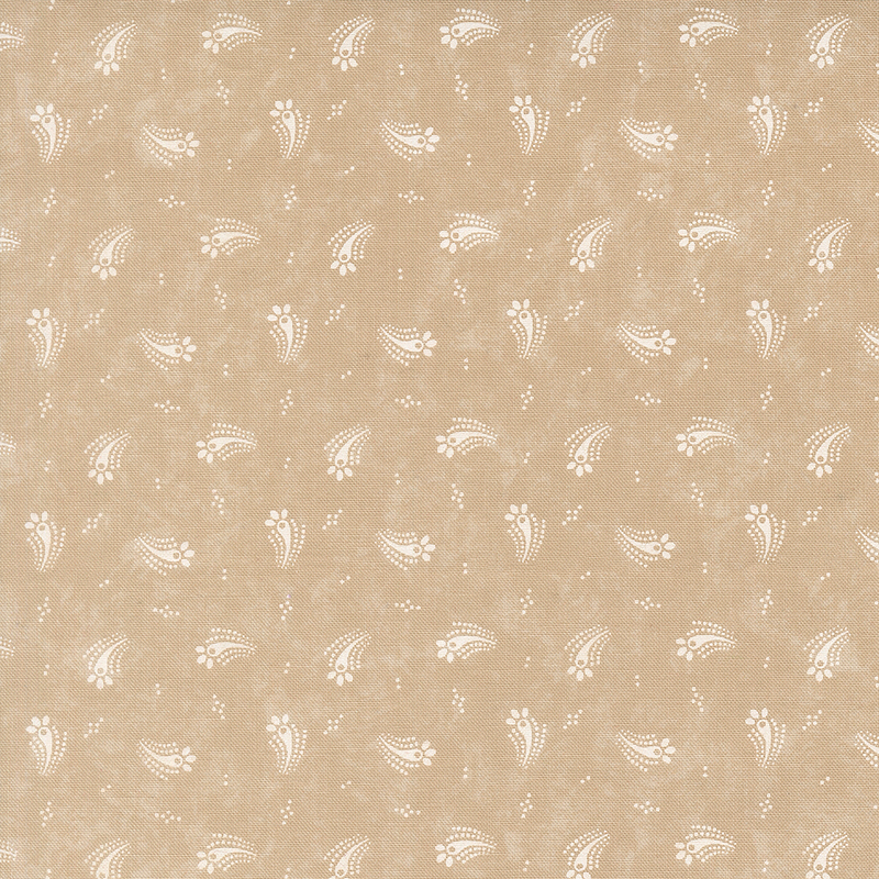 Tan fabric with a tossed design of cream dots and abstract cream floral motifs.