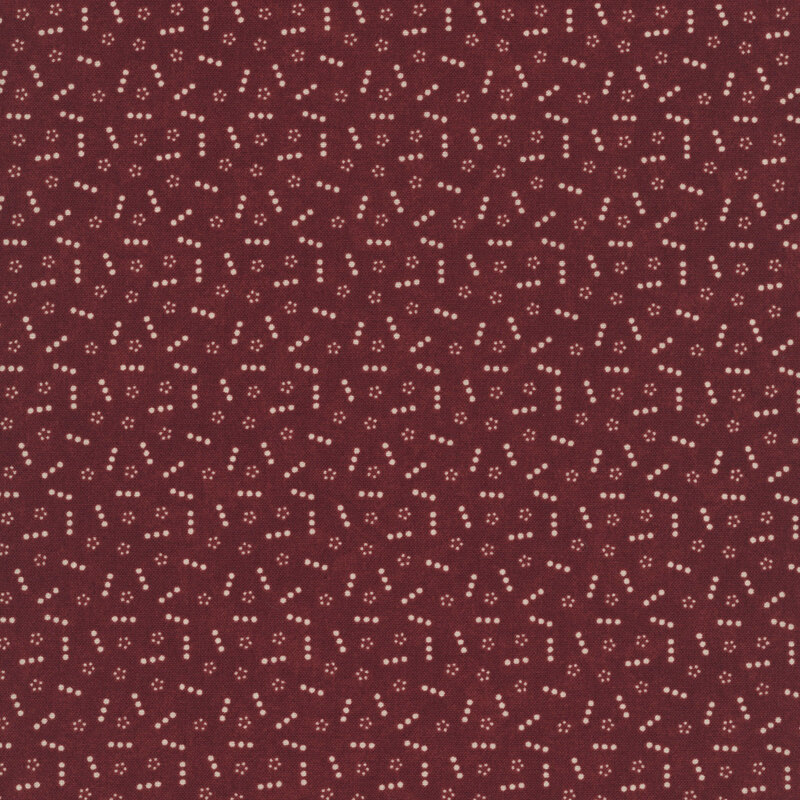 Red fabric topped with a scattered pattern of lines and groups of small tan dots.