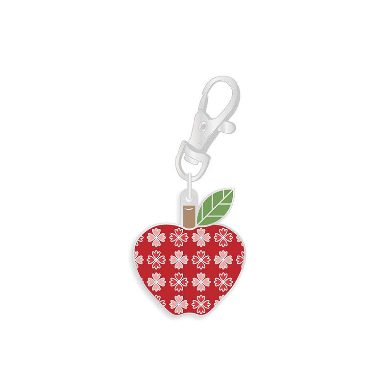 Enamel pin with a clip holding a plump red apple decorated with a grid of pink and red florals isolated on a white background.