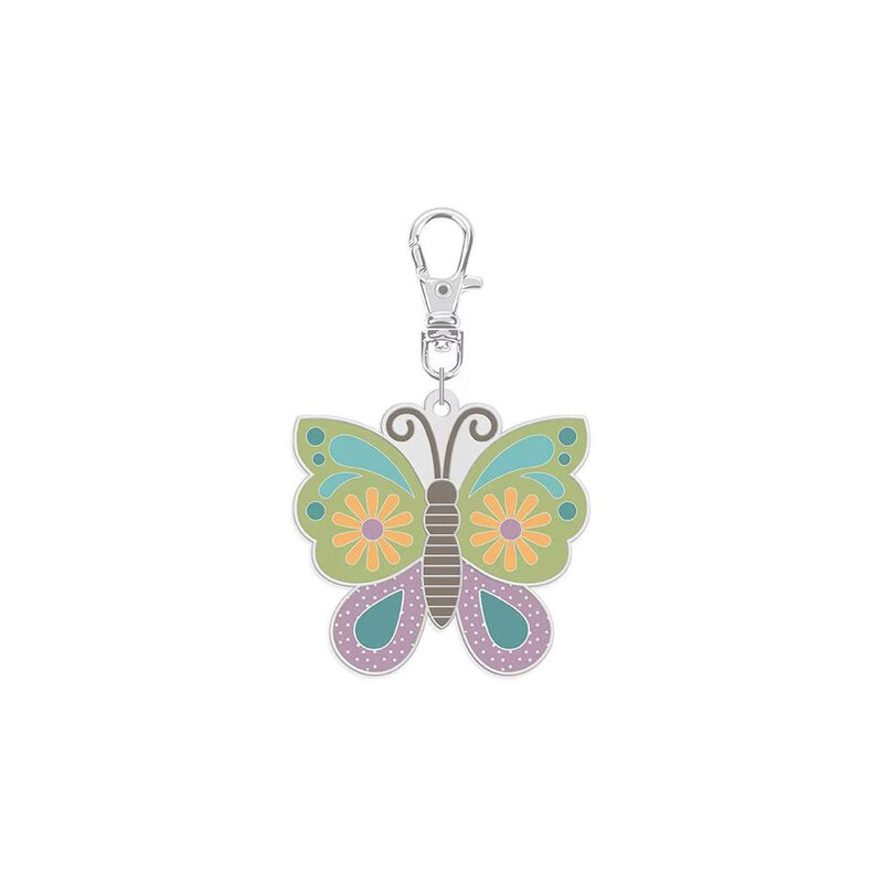 Enamel pin with a clip holding a green and purple butterfly with yellow florals isolated on a white background.