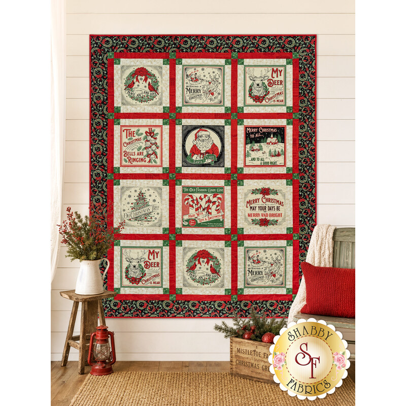 The completed Holiday Cheer Panel Quilt, colored in black, cream, red, and green fabrics, hung on a cream shiplap wall and staged with coordinating furniture and décor.