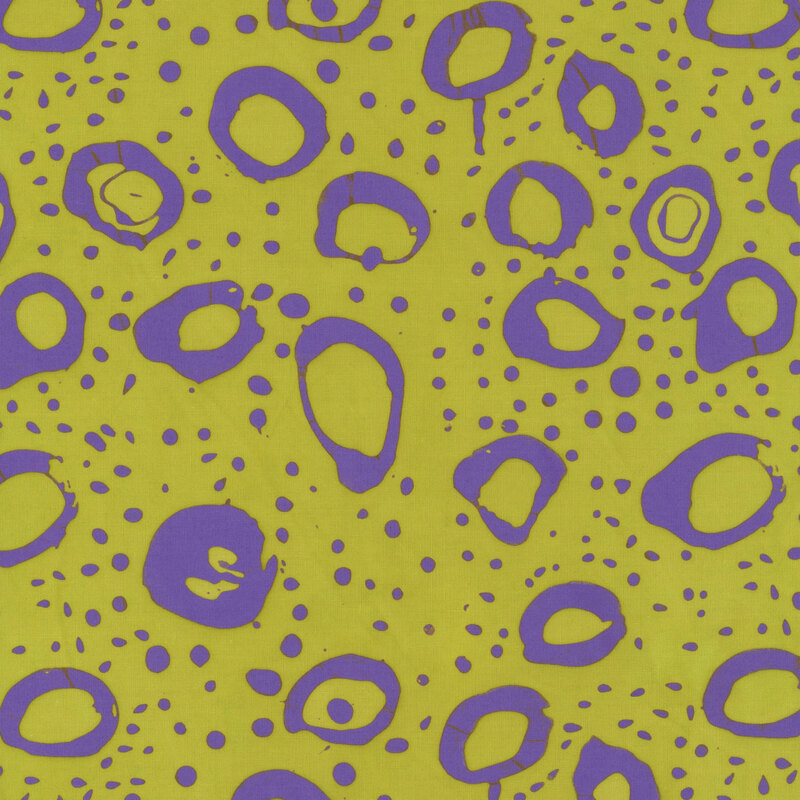 Citron green fabric with irregular stamped circles and dots in purple.