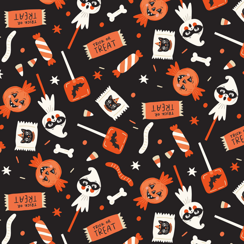 A black glow in the dark fabric with scattered Halloween candies. 