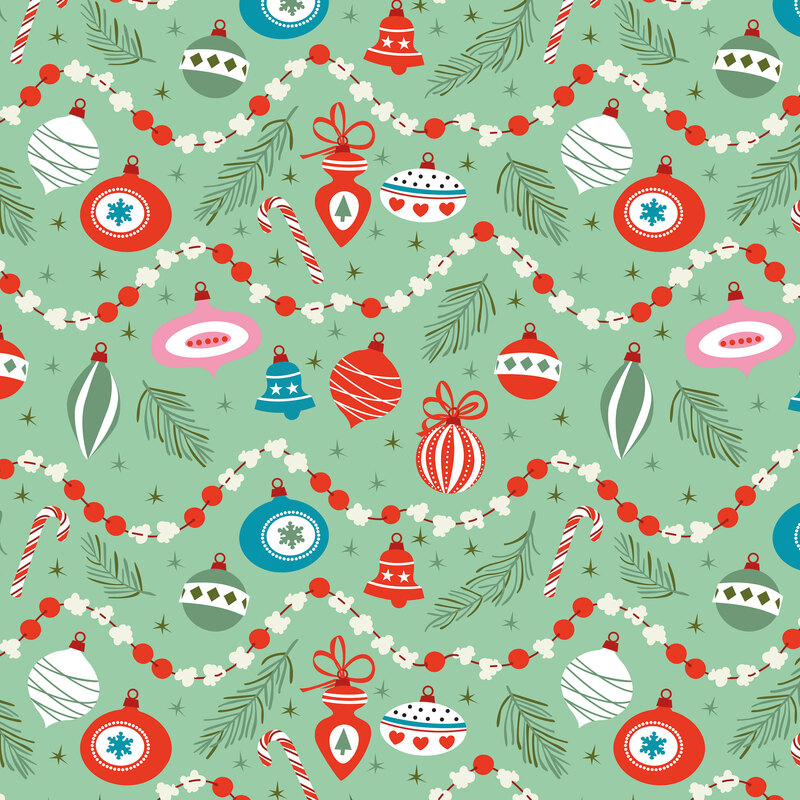 Mint green fabrics scattered with pine sprigs, Christmas ornaments, stars, and ornament strings.