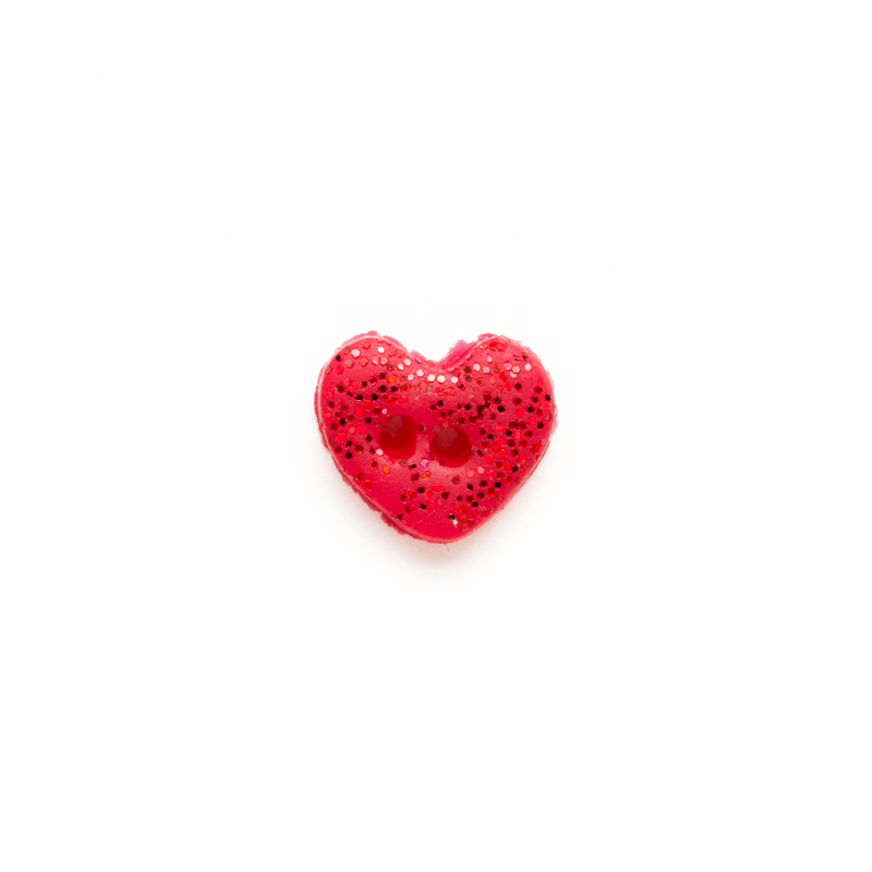 One small red glittery clay heart button, isolated on a white background. 