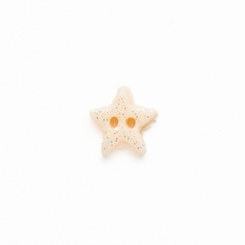 Tiny glittering ivory clay star button, isolated on a white background. 