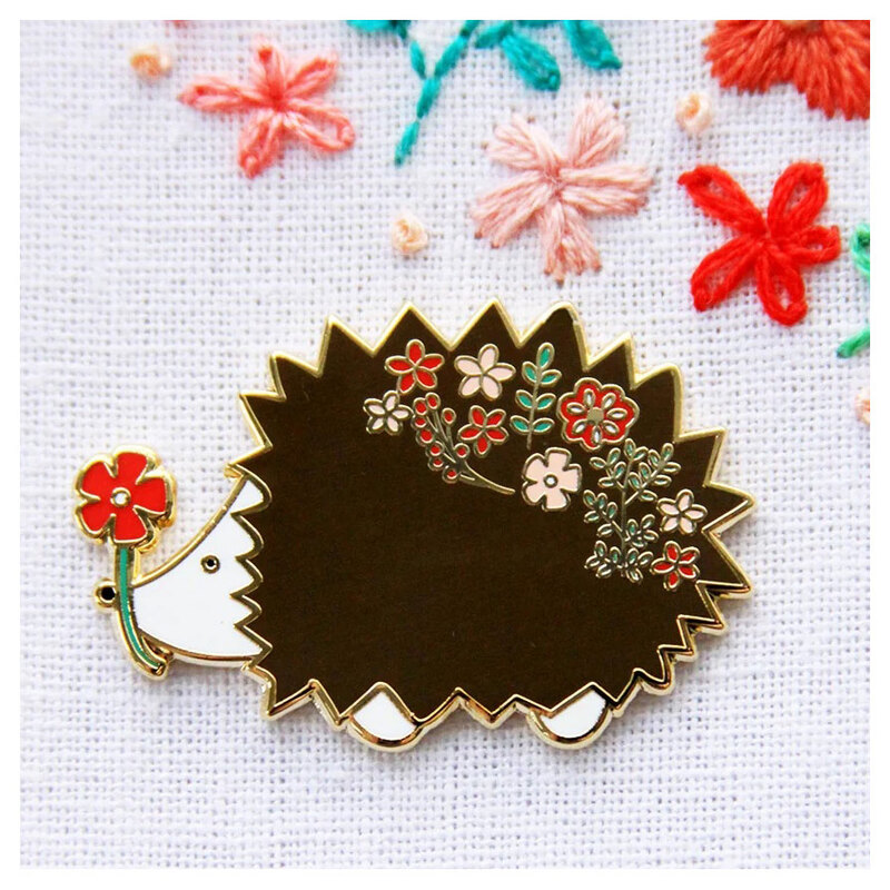 The floral hedgehog needle miner displayed on a hand embroidery project.