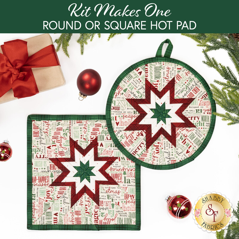 The two completed Folded Star Hot Pads colored in red, cream, and mint green fabrics from the Evergreen Wishes collection by Riley Blake Designs, slightly overlapping each other and staged on a white table with coordinating décor.