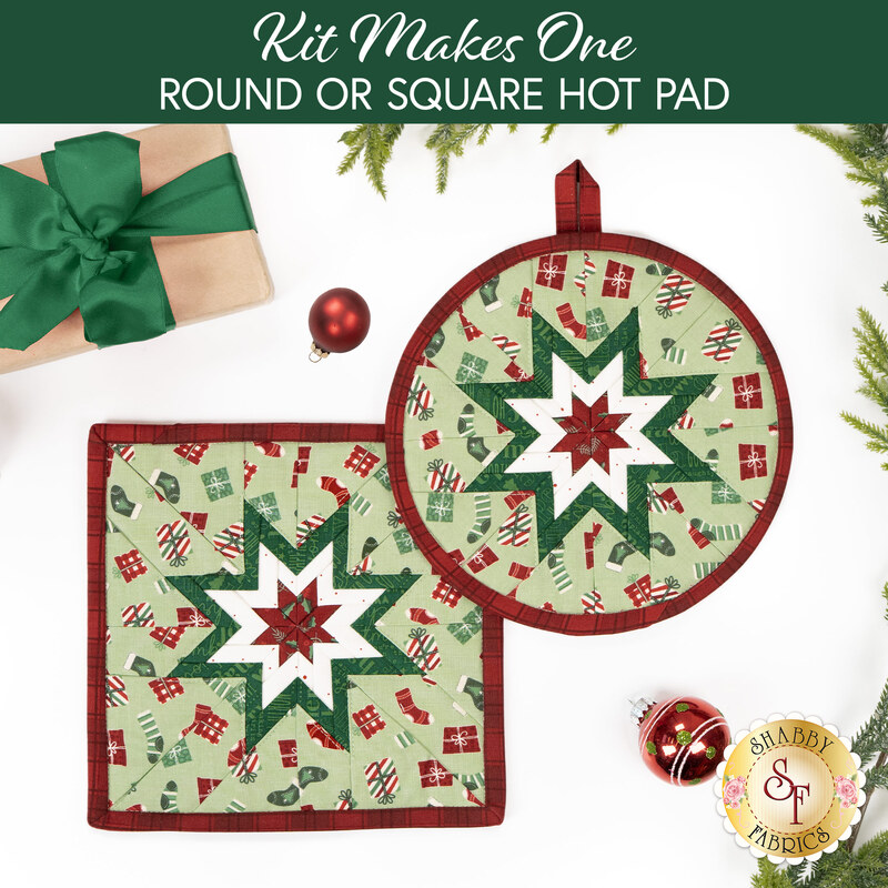 The two completed Folded Star Hot Pads colored in red, cream, and mint green fabrics from the Evergreen Wishes collection by Riley Blake Designs, slightly overlapping each other and staged on a white table with coordinating décor.