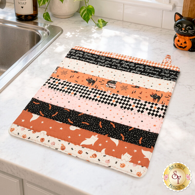 The completed Dry Ideas project, colored in Halloween fabrics from the Purrs & Boos collection by Moda Fabrics, staged on a white marbled kitchen counter with coordinating décor.