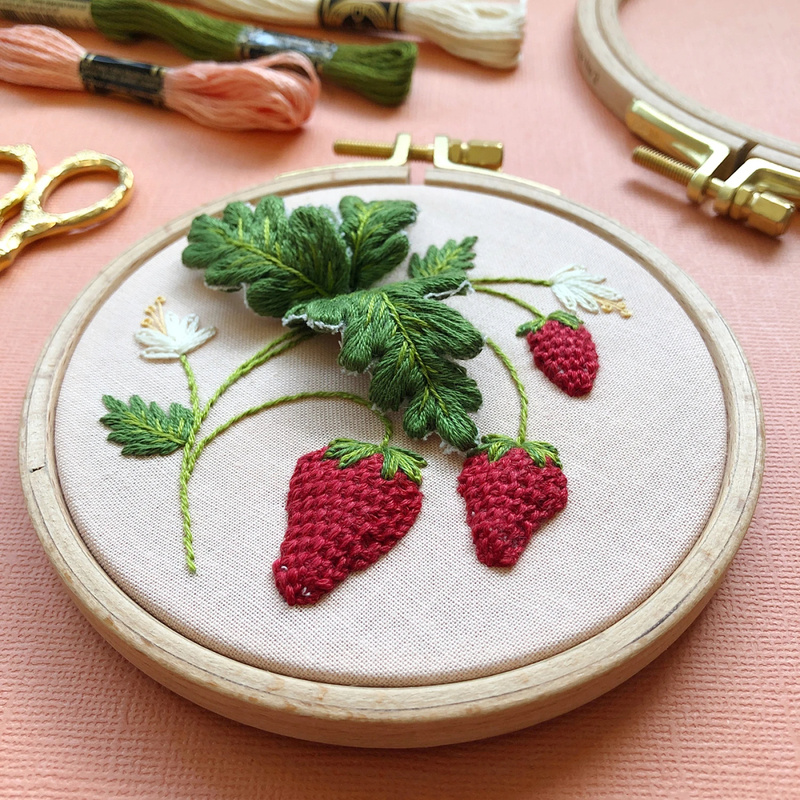 Stumpwork Strawberries Embroidery Kit packaging featuring a hoop with three-dimensional red strawberries, green leaves, and white flowers stitched on pale peach fabric.