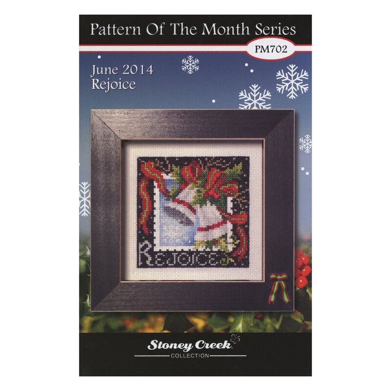 Front of the Pattern of the Month Series Rejoice cross stitch pattern with the finished design in a black wooden frame isolated on a wintry scene.