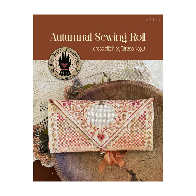 Front cover of the Autumnal Sewing Roll cross stitch pattern displaying the finished design folded up and placed on a log next to a white doily.