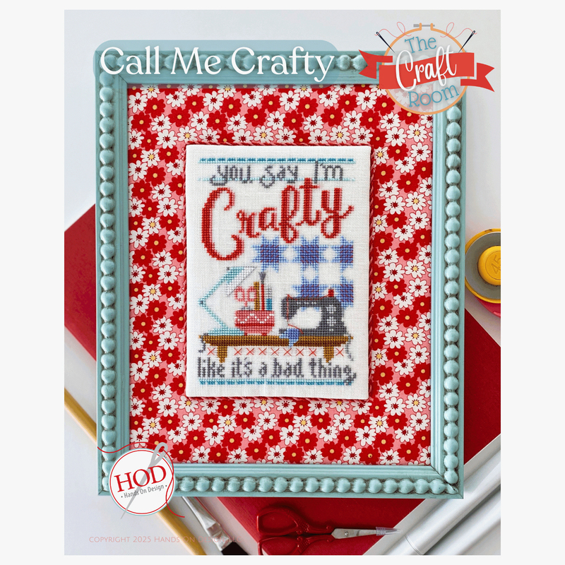 Image of the Call Me Crafty cross stitch project finished and framed, staged with crafting supplies.