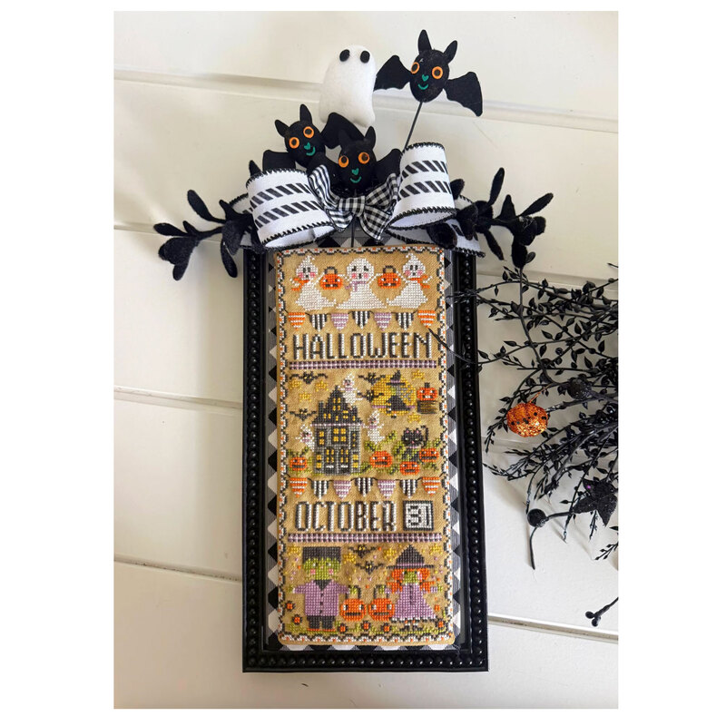 The completed halloween cross stitch design finished with several borders and decorated with halloween décor. 