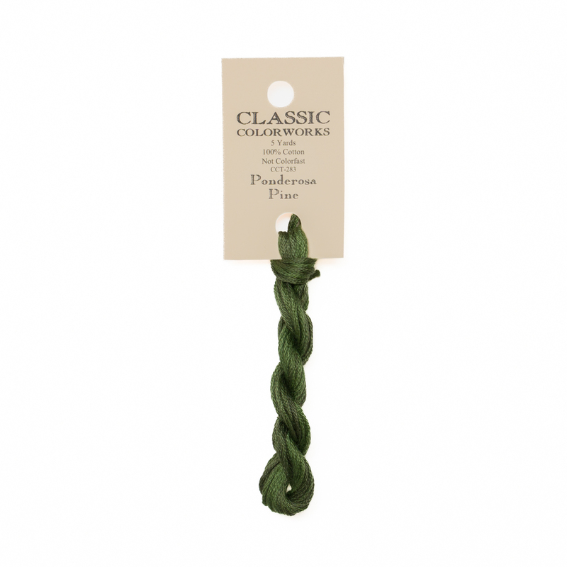 A skein of pine green embroidery floss, twisted and bundled, with a cream and black label featuring the brand name and color information.
