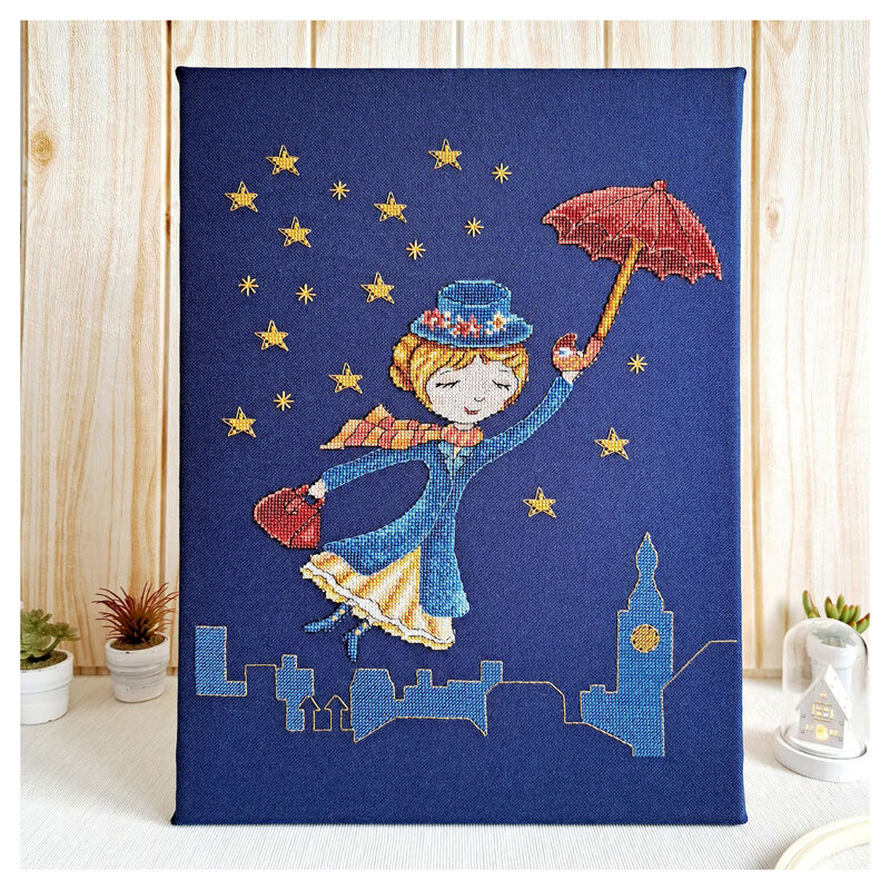 The Mary Poppins cross stitch pattern finished and staged with small potted plants and a light wood background.