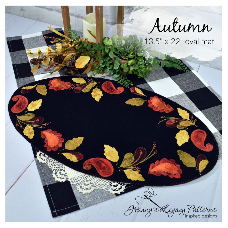 The completed Autumn Wool Mat, embroidered with elegant autumnal colors, staged on a picnic table with coordinating décor.