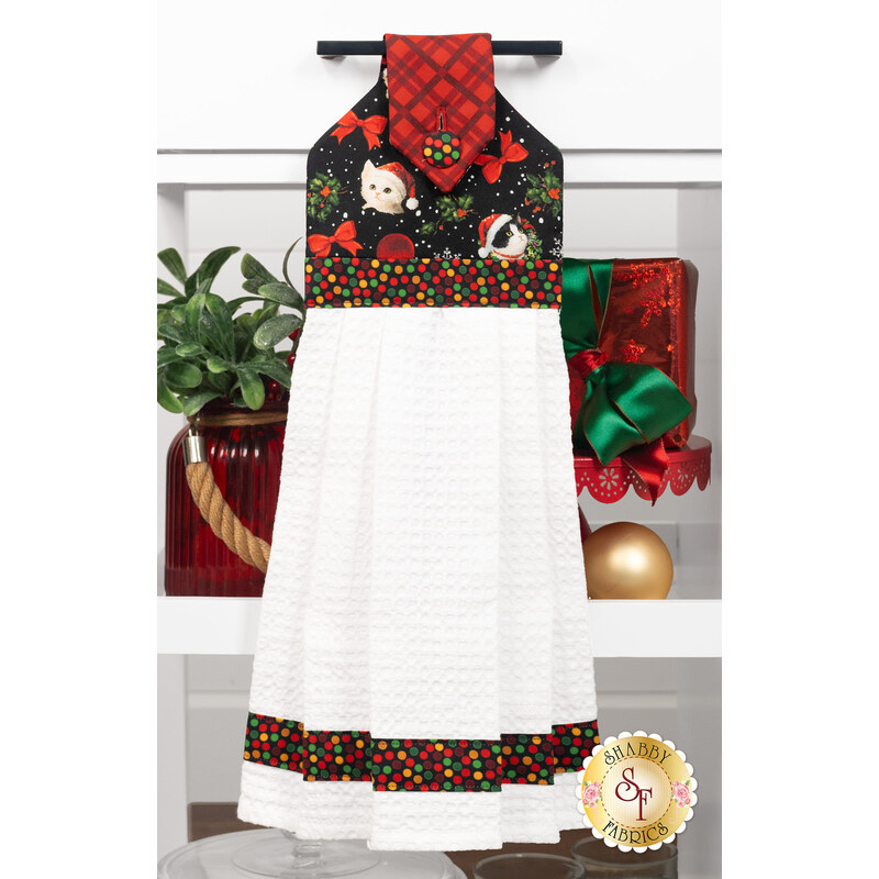 The completed Hanging Towel colored in black, red, and green fabrics from the Merry Cats collection by Benartex, staged on a kitchen drawer with coordinating decor.