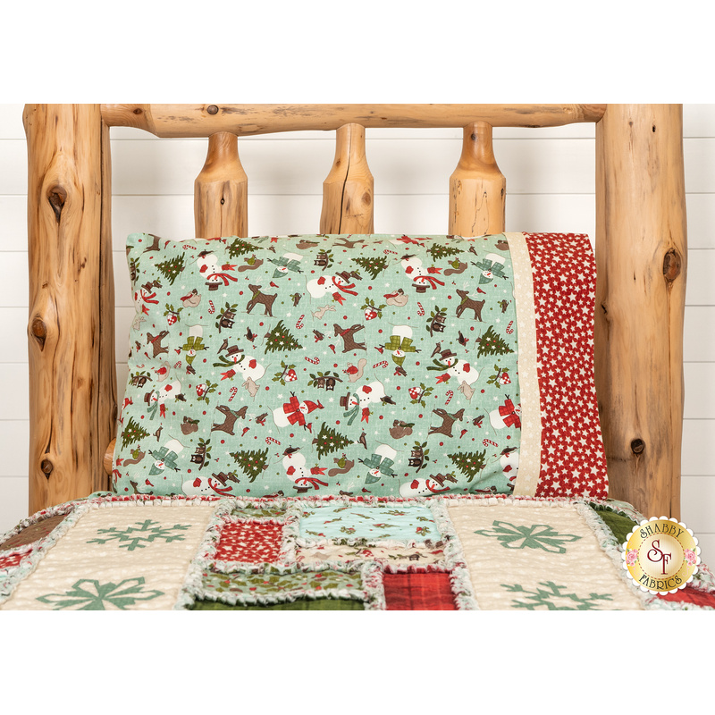 The completed Magic Pillowcase colored in fabrics from the Snowtop Mountain Flannel collection by Maywood Studio, staged on a log cabin bed with a coordinating quilt.