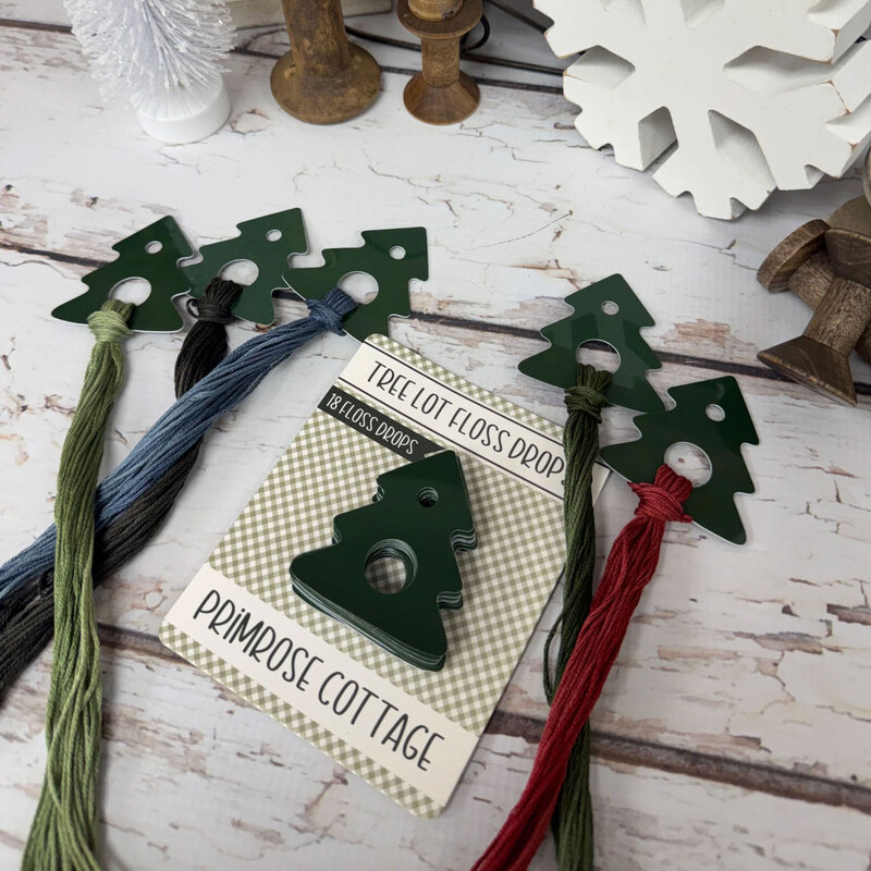 The tree lot floss drops by Primrose Cottage Stitches displayed with floss and in their packaging. 
