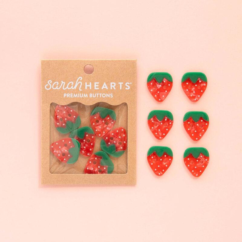 A pack of 6 strawberry buttons, isolated on a pink background.