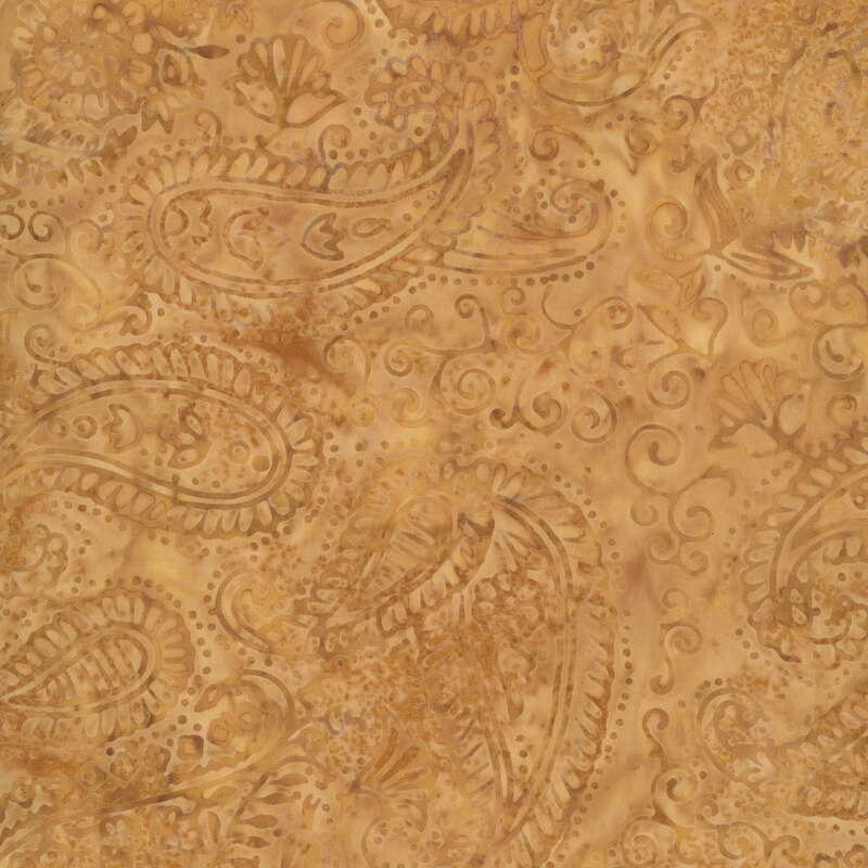 warm gold batik fabric featuring intricate tonal paisley motifs, swirling vines, and delicate floral accents in soft shades of honey, amber, and caramel against a subtly mottled background.
